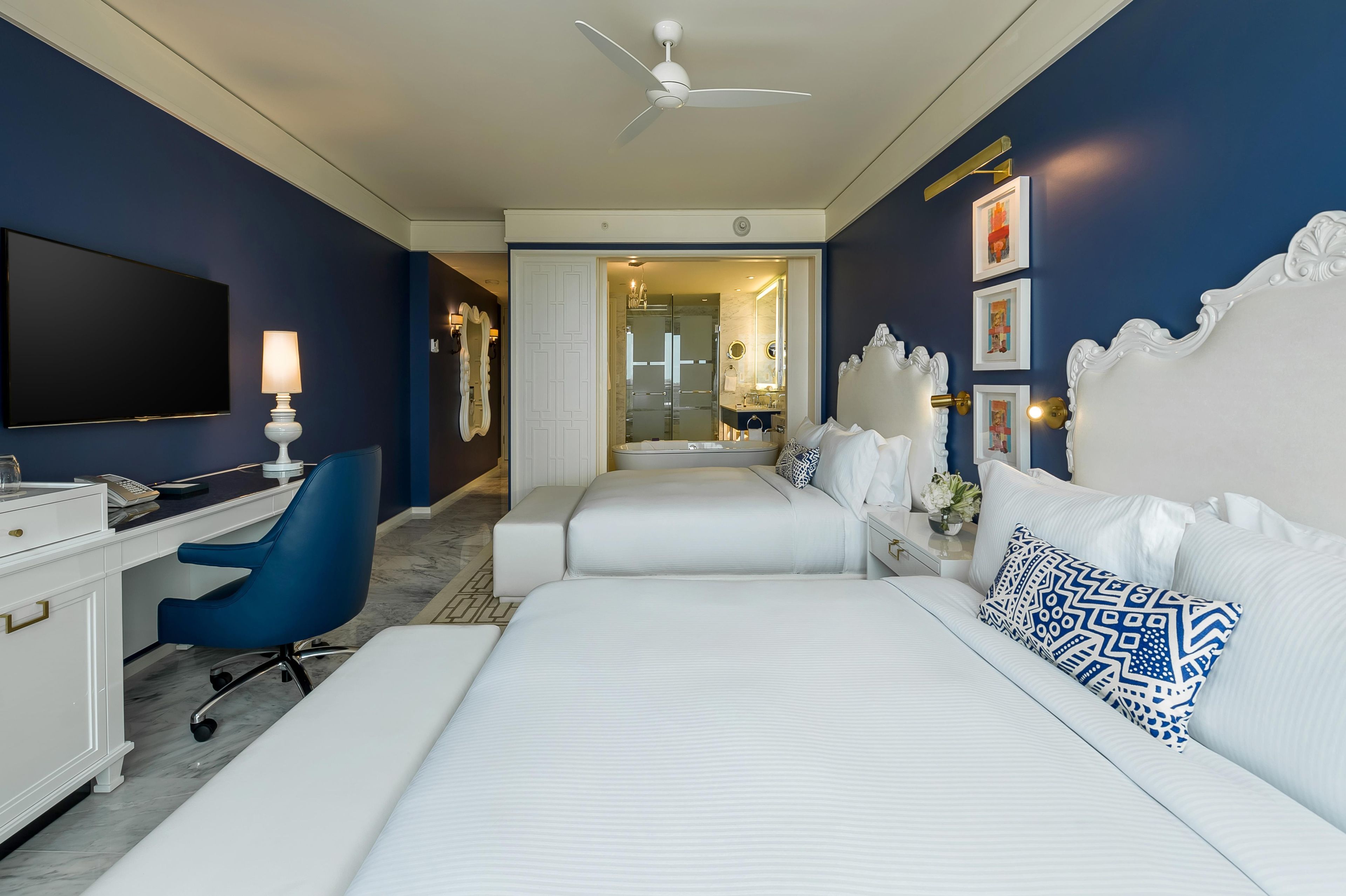 Une chambre d’hôtel avec un grand lit, un bureau, une chaise et un téléviseur.