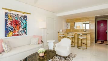 A modern living room with a white sofa, a glass coffee table, and a colorful abstract painting.
