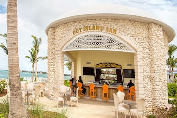 A modern building with a glass facade, palm trees, and a paved walkway. at Grand Hyatt Baha Mar