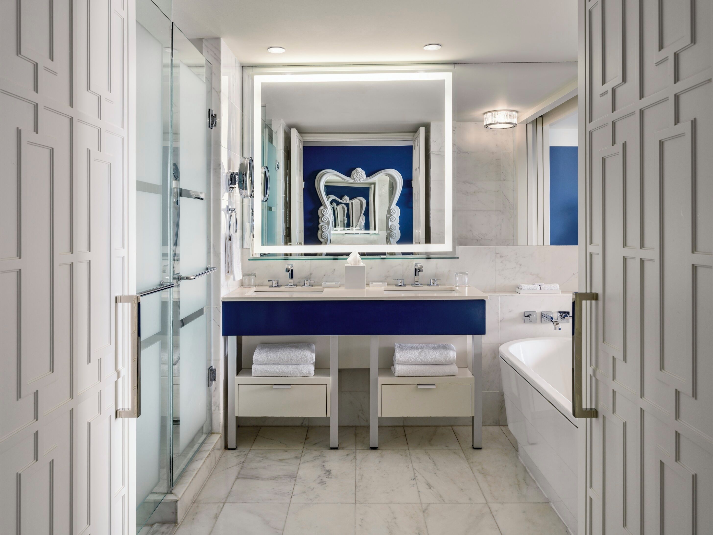 Un baño moderno con cabina de ducha de vidrio, tocador doble y un espejo grande.