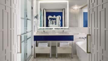 Un baño moderno con cabina de ducha de vidrio, tocador doble y un espejo grande.