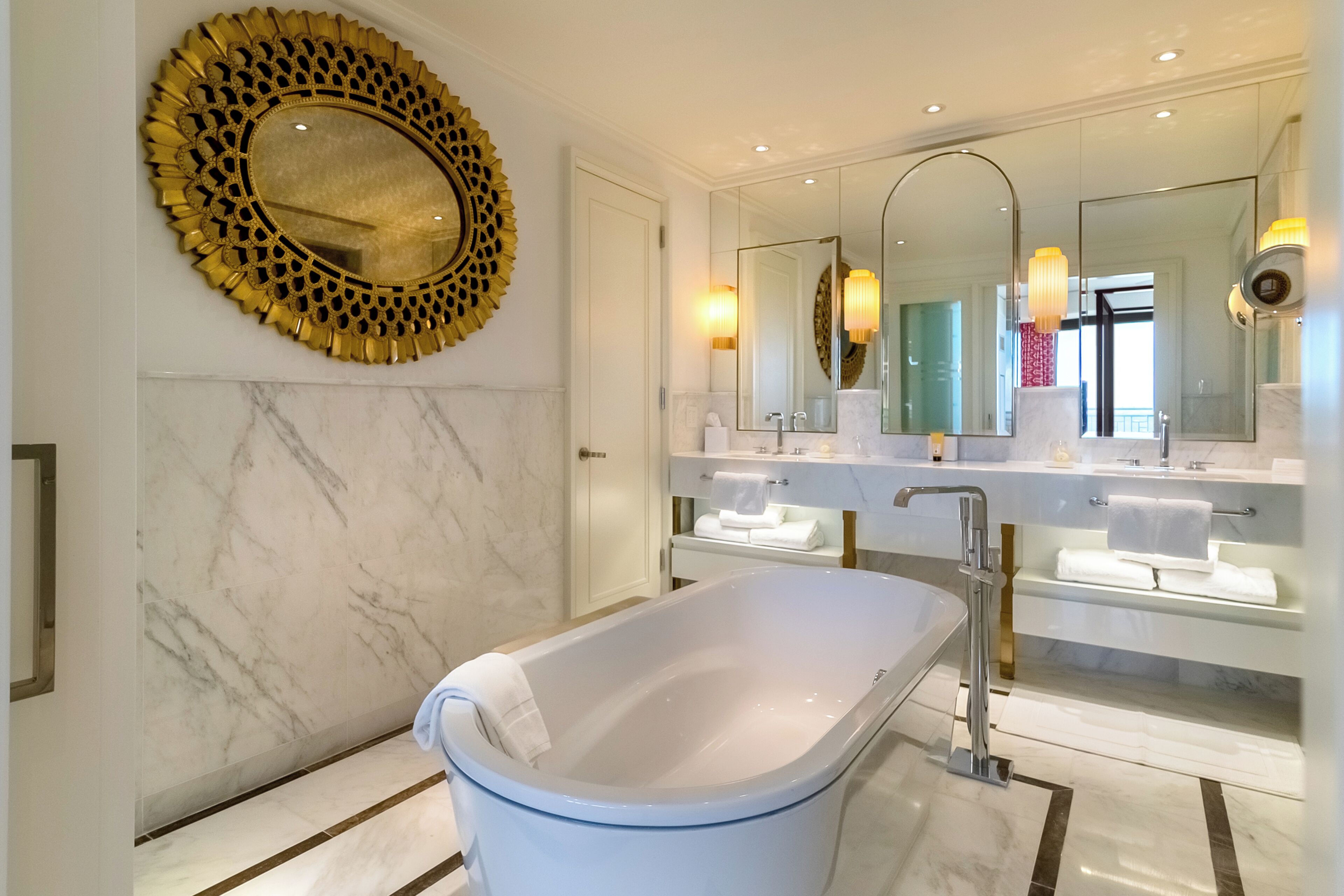 Un bagno moderno con una vasca freestanding, uno specchio ampio e un elemento decorativo a parete.