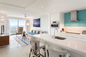 A modern kitchen with a large island, white cabinetry, and a view to the outside.