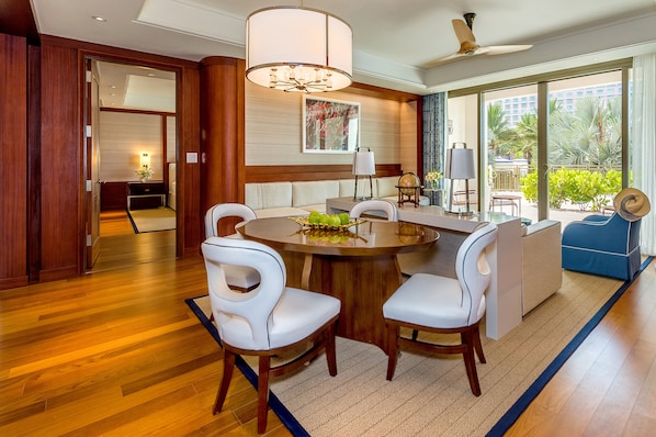 A modern dining area with a round table, white upholstered chairs, and a chandelier. - Grand Hyatt Baha Mar (Nassau)