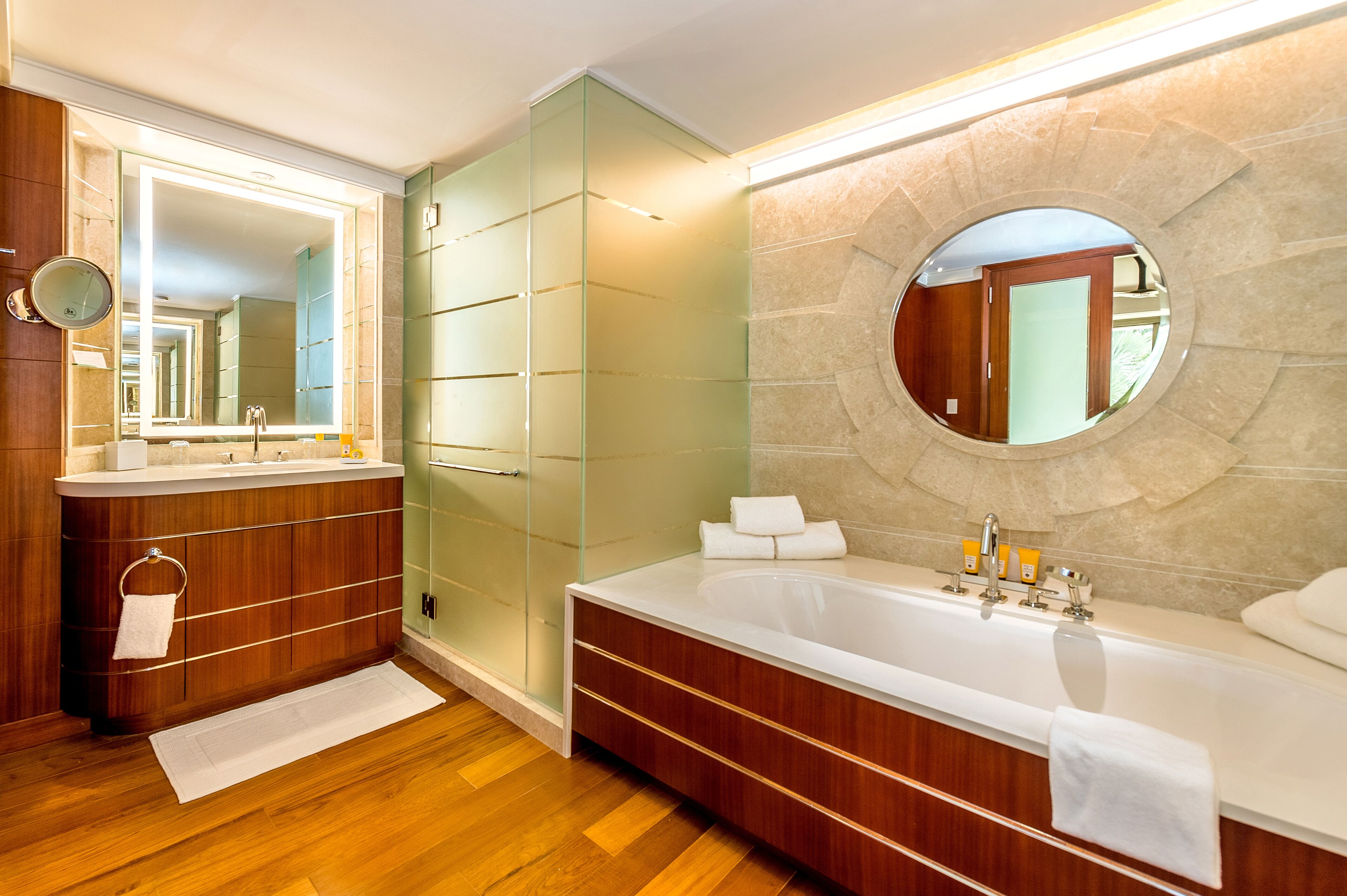 A modern bathroom with a large bathtub, a glass-enclosed shower, and a vanity with a mirror.