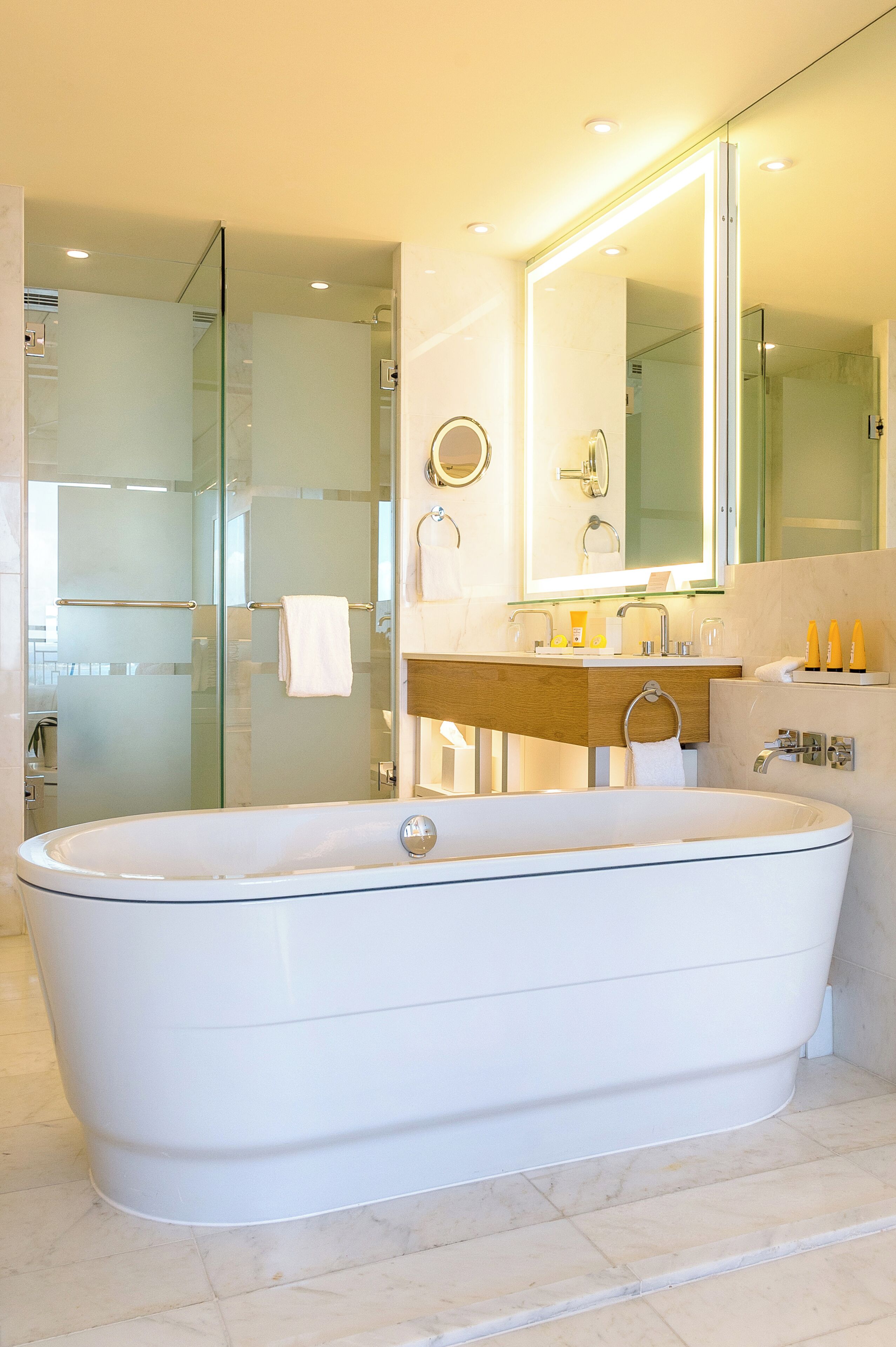 A modern bathroom with a freestanding bathtub, a glass-enclosed shower, and a vanity with a mirror.