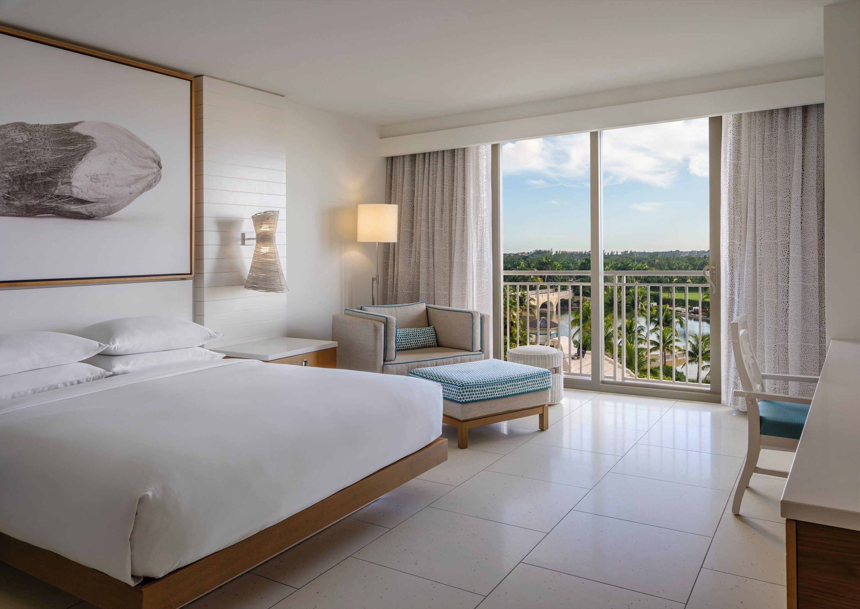 Une chambre d’hôtel avec un grand lit, un bureau, une chaise et un balcon avec vue.