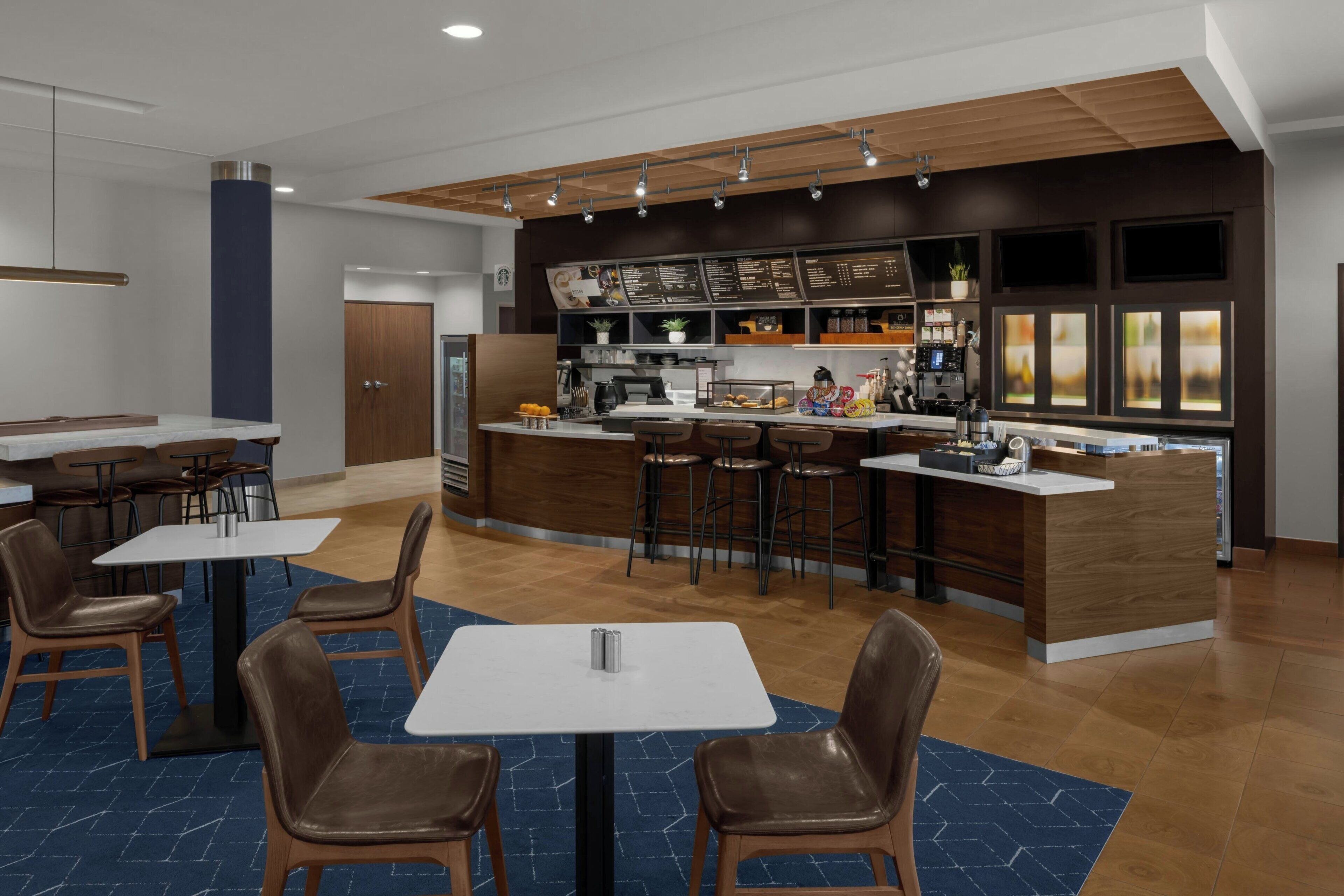 A modern restaurant with a bar area, multiple seating options, and a visible menu board.