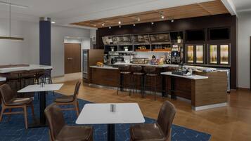 A modern restaurant with a bar area, multiple seating options, and a visible menu board.