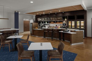 Um restaurante moderno com área de bar, diversas opções de assentos e um cardápio à vista.
