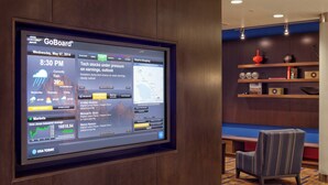 Un écran GoBoard® installé dans le hall d’un hôtel, affichant une carte, un bulletin d’informations et un graphique de l’indice Dow Jones.