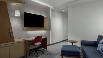 Habitación de hotel con escritorio, silla, televisor, sofá y una mesita.