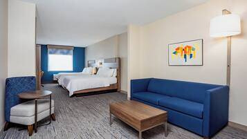 Une chambre d’hôtel avec un lit, un canapé bleu, une petite table et une chaise.