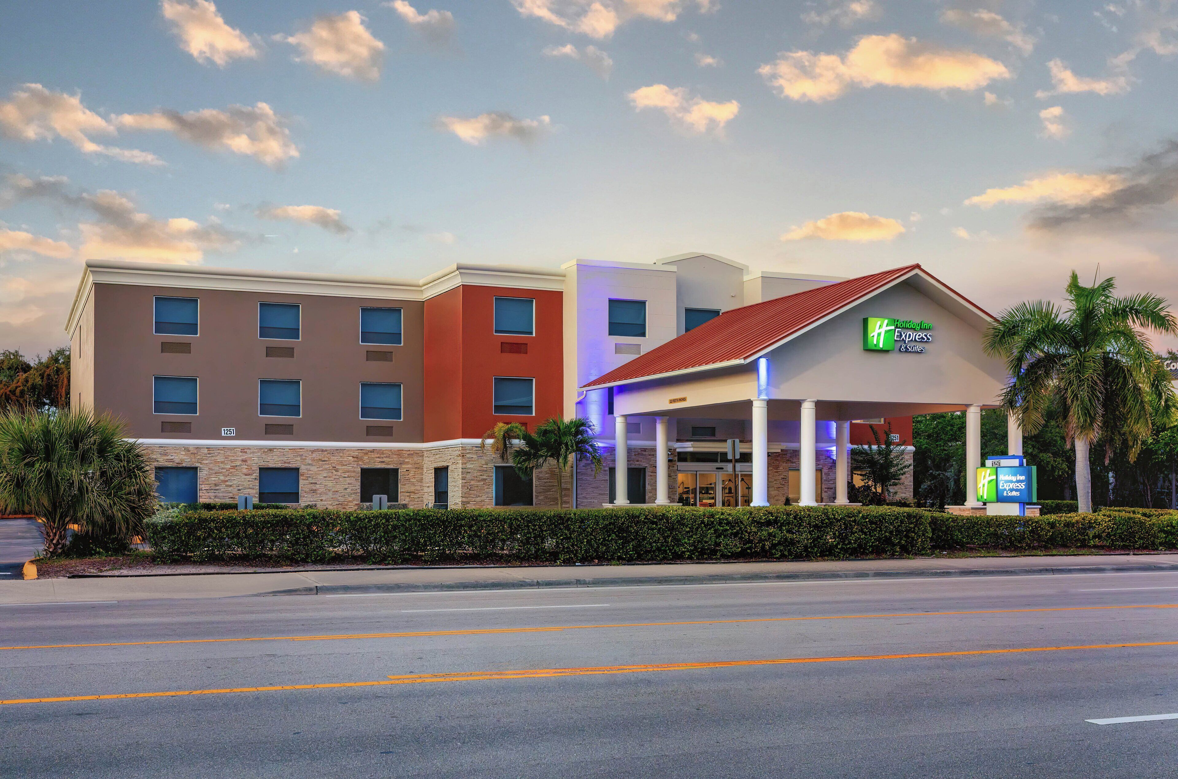 Un hôtel Holiday Inn Express doté d’une façade moderne, de plusieurs entrées et d’une pelouse bien entretenue.