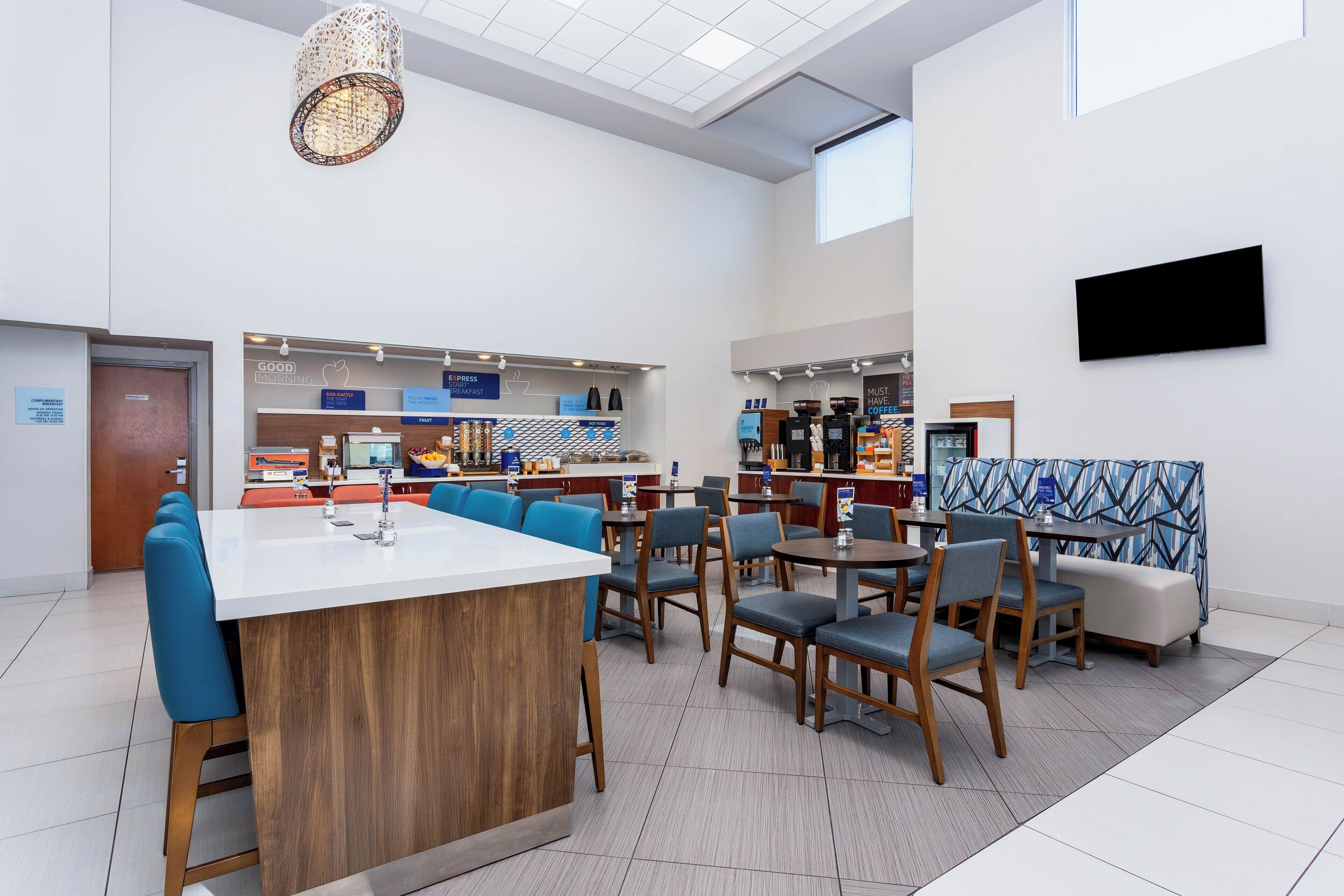 Una cafetería moderna con una isla central, zona de estar y barra de café.