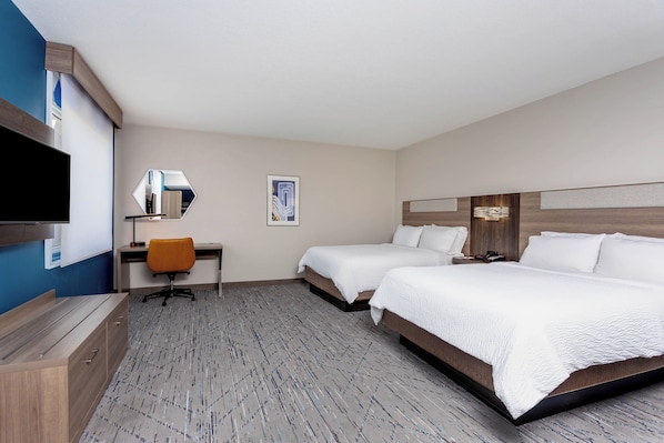 A hotel room with a bed, a desk, a chair, a television, and a painting on the wall. - Holiday Inn Express & Suites Lantana by IHG (Lantana)