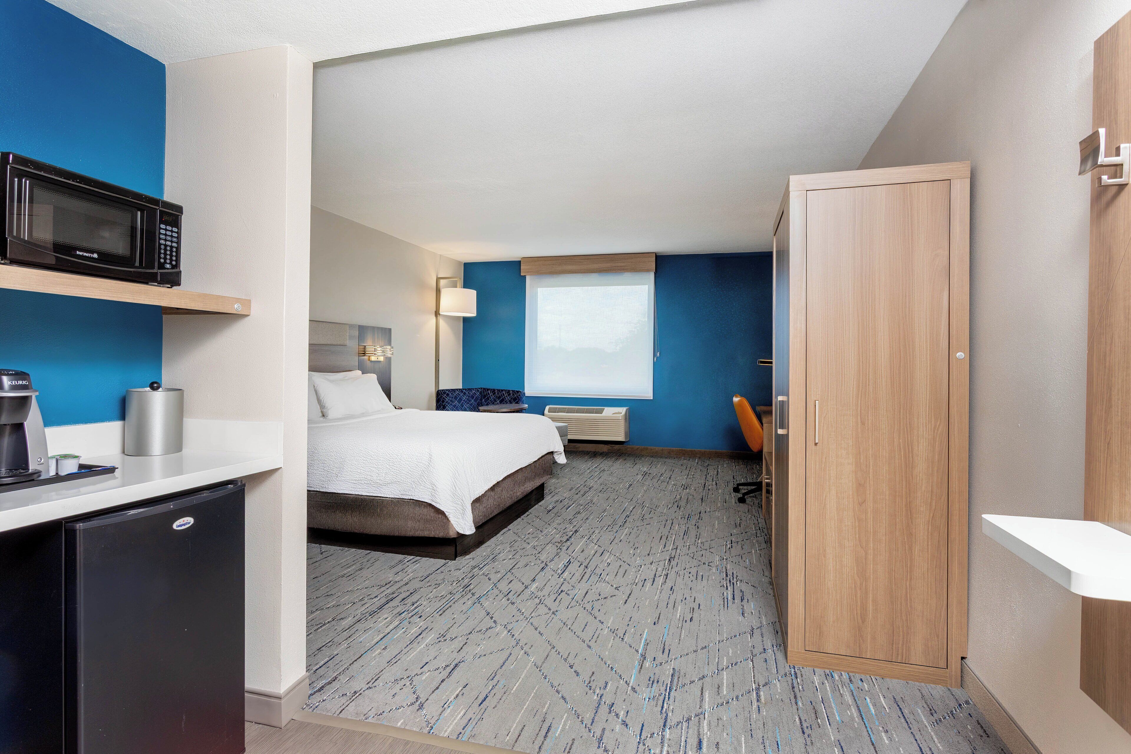 Ein Hotelzimmer mit Bett, Schreibtisch, Mikrowelle, Minikühlschrank und einem Fenster mit Aussicht.