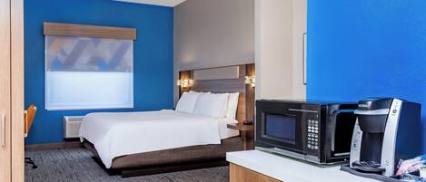Une chambre d’hôtel équipée d’un lit, d’un mini-bar, d’un four à micro-ondes et d’une machine à café.