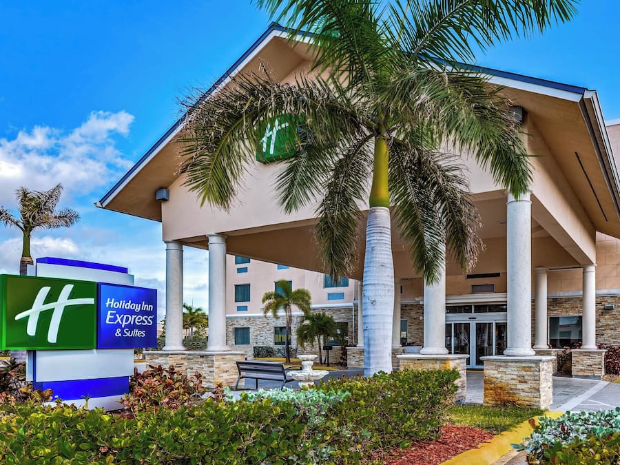 Edificio de Holiday Inn Express & Suites con diseño moderno, que presenta una entrada amplia con columnas, un área cubierta y un cartel.