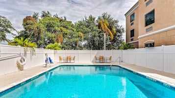 Relax by the pool surrounded by lush greenery and comfortable seating.