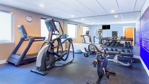A gym with treadmills, an elliptical, a rowing machine, and a rack of dumbbells.