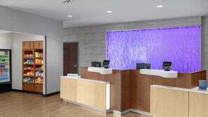 A hotel reception area with a wooden reception desk, a self-service kiosk, and a snack vending machine. - Fairfield Inn & Suites Calhoun (Calhoun)