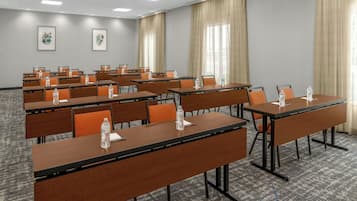 Une salle de conférence dotée de plusieurs tables et chaises, ainsi que de bouteilles d’eau et de plaques nominatives.