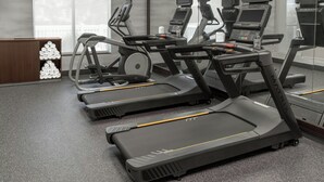 A gym with treadmills, exercise bikes, and a wooden cabinet with towels. - Fairfield Inn & Suites Calhoun (Calhoun)