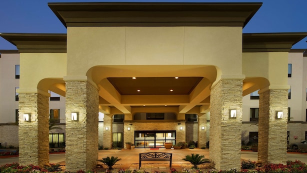 A hotel entrance with stone pillars, a covered walkway, and a central seating area. - Hampton Inn Lake Charles (Lake Charles)