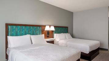 Una habitación de hotel con dos camas, una mesita de noche y una lámpara fijada a la pared.