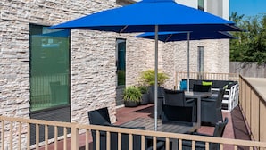 An outdoor patio with stone walls, a blue umbrella, and outdoor furniture. - Hampton Inn Lake Charles (Lake Charles)