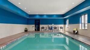 A swimming pool with a blue and white color scheme, surrounded by a tiled deck, and equipped with a changing room and seating area. - Hampton Inn Lake Charles (Lake Charles)