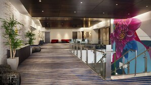 A modern hotel lobby with a patterned carpet, glass railings, and a large floral mural. - Residence Inn Los Angeles L.A. LIVE (Los Angeles)