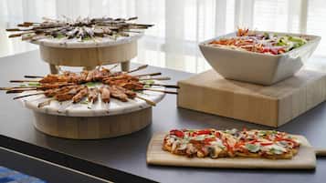 Une table de buffet avec des brochettes, une salade et une pizza.