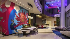 A modern lobby with a large floral mural, a round dining table, and a seating area with red sofas. - Residence Inn Los Angeles L.A. LIVE (Los Angeles)