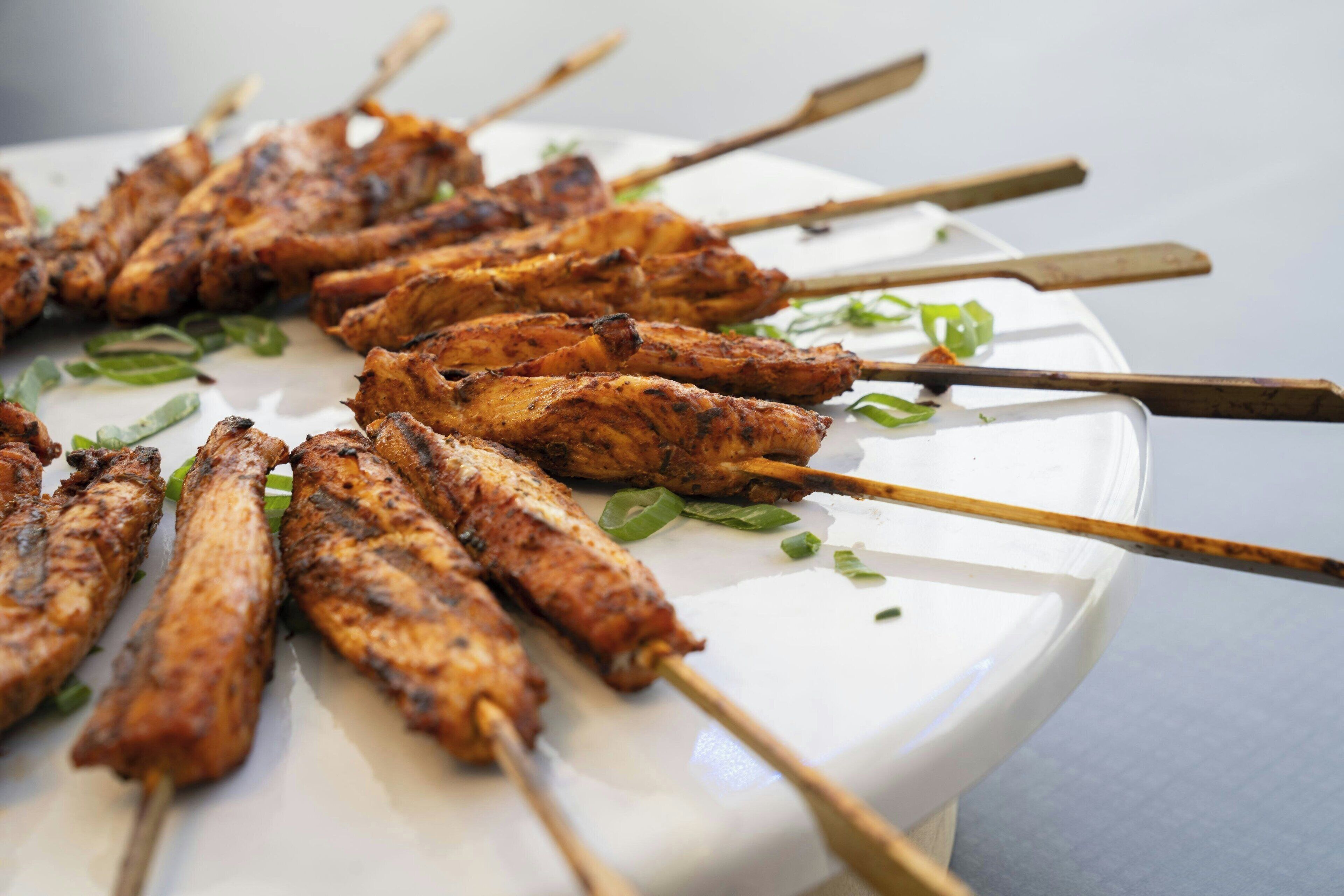 A plate of grilled skewers arranged on a white plate.