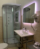 Un bagno moderno con doccia a vetro, un lavabo con mobile contenitore e uno specchio con asciugacapelli integrato.