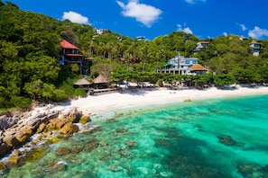 A coastal resort with beach access, clear turquoise waters, and lush greenery.