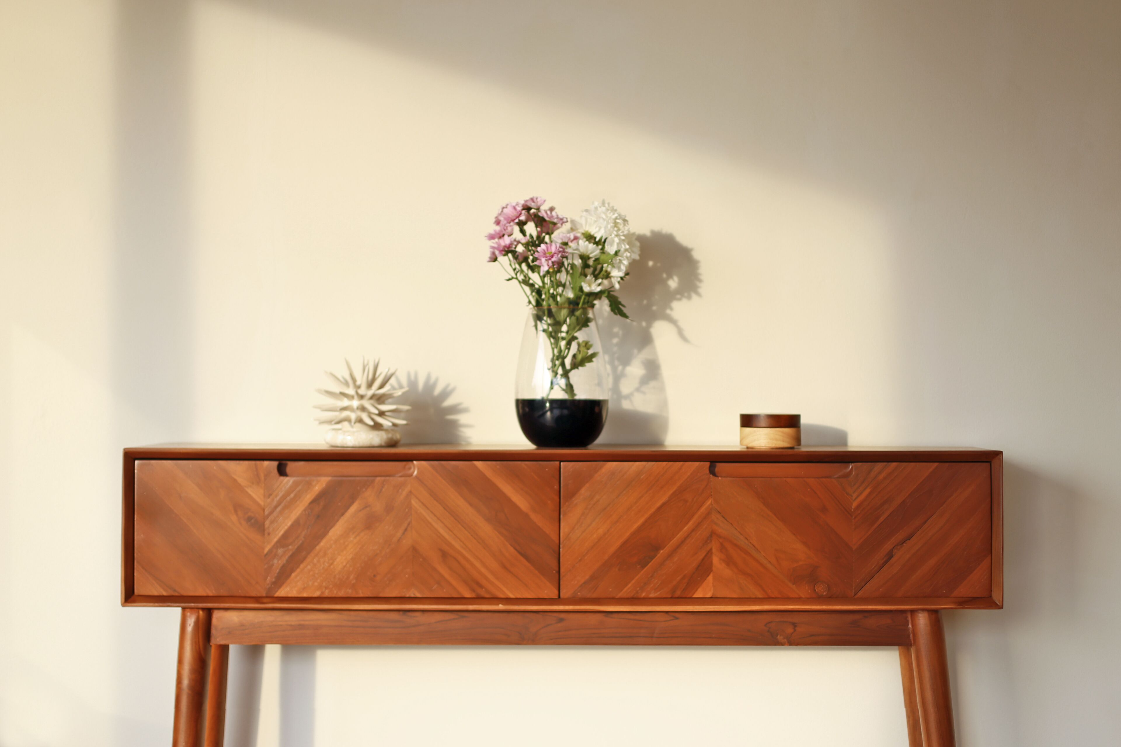 A wooden console table with a vase of flowers and decorative items.
