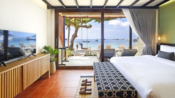 A hotel room with a large bed, a TV, and a view of the sea. - Lücke Boutique Hotel (Koh Tao)