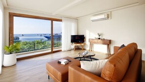 A modern living room with a large window, a flat-screen TV, a sofa, and a coffee table. - Lücke Boutique Hotel (Koh Tao)