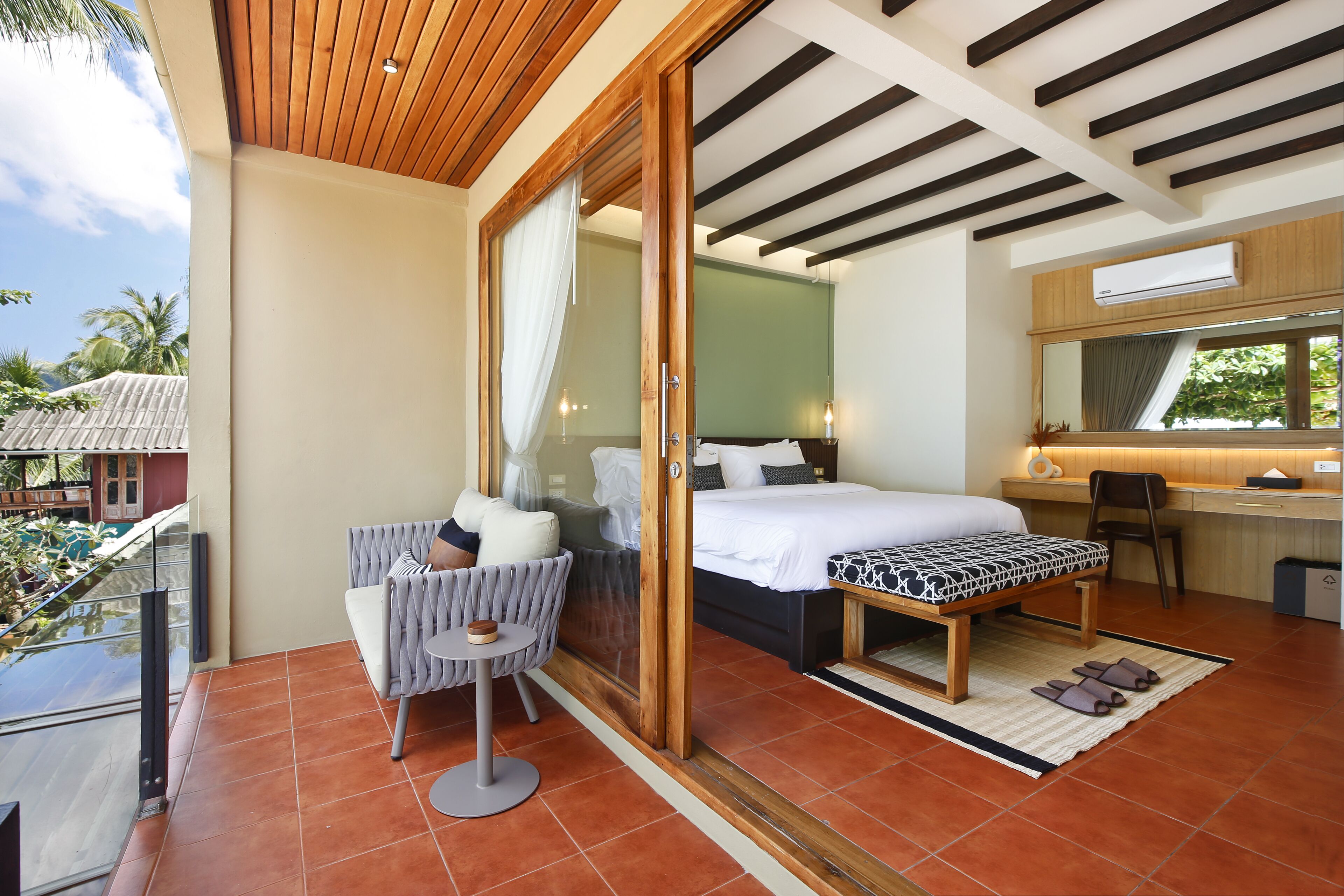 A modern hotel room with a balcony, a bed, a desk, and a chair.