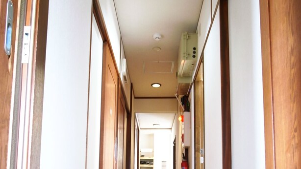 A long, narrow hallway with wooden paneling and a shiny tiled floor. - Andon Makishikan (Naha)