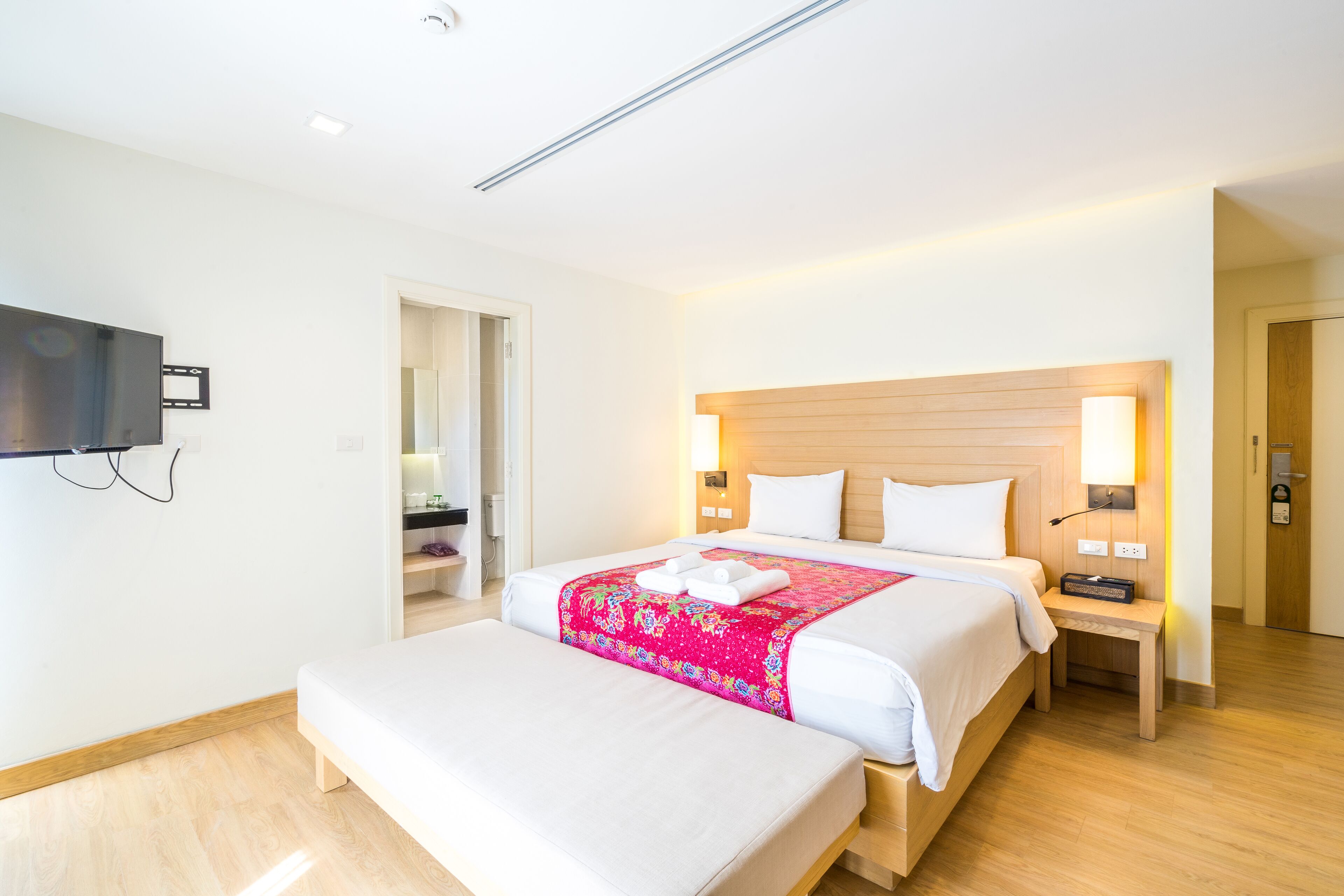 Habitación de hotel con una cama grande, mesitas de noche, un televisor de pantalla plana y un cabecero de madera.