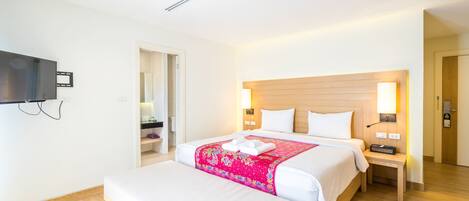 A hotel room with a large bed, bedside tables, a flat-screen TV, and a wooden headboard.