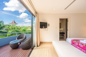A modern hotel room with a balcony, a bed, a TV, and a view of a temple. - Baan Suwantawe (Phuket)