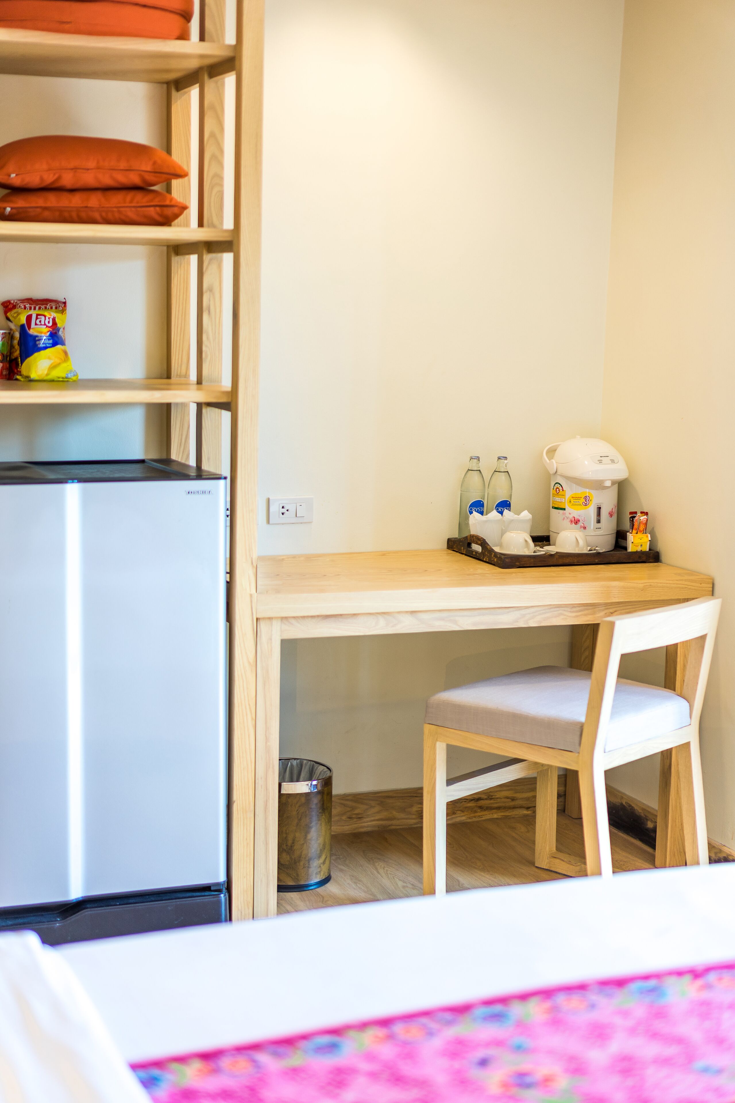 A compact kitchenette with a refrigerator, a coffee maker, and a trash bin.