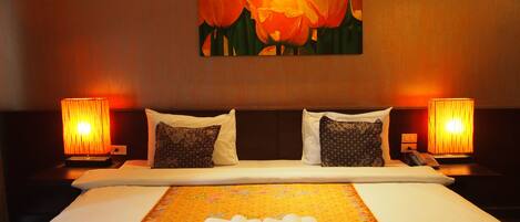 A hotel room with a large bed, two bedside lamps, and a painting of tulips on the wall.