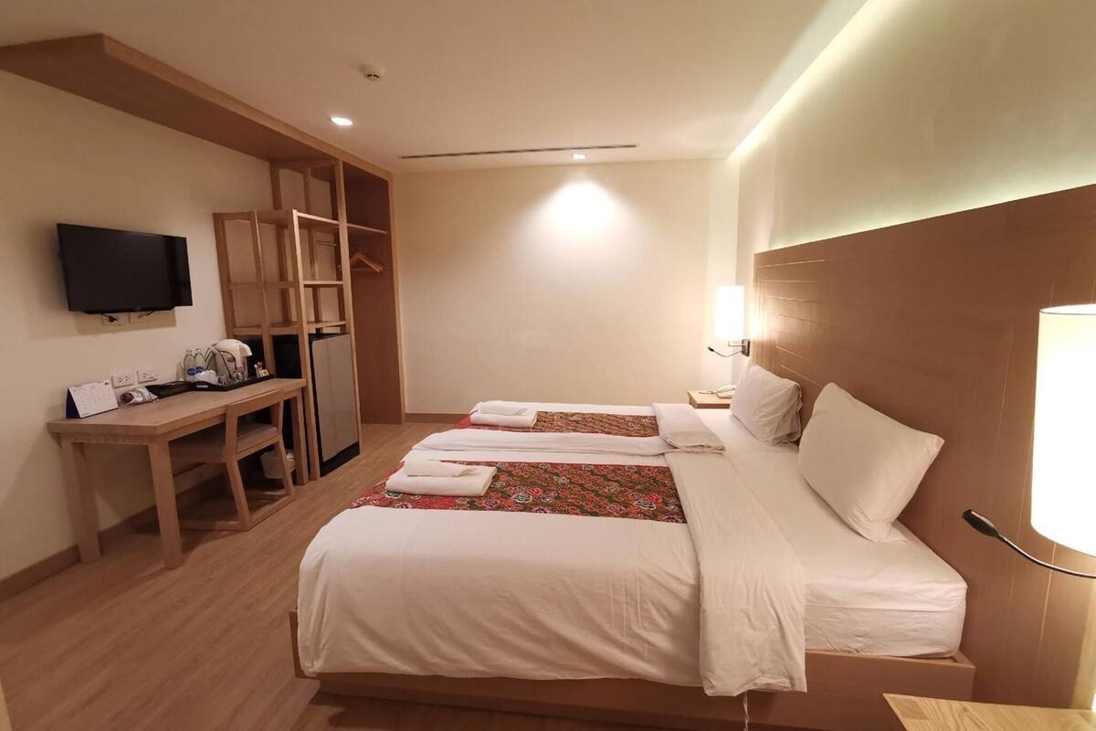 A hotel room with a bed, a desk, a television, and a wardrobe.
