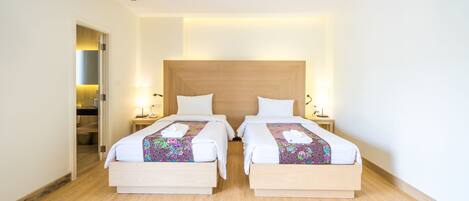 A hotel room with two beds, wooden flooring, and a large wooden headboard.